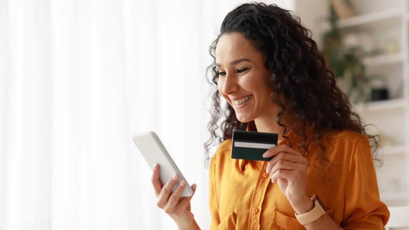 Happy customer with credit card looking at smartphone