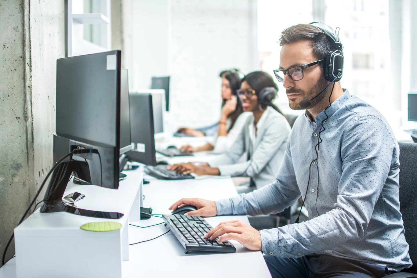 man-with-headset-and-others-looking-at-computer