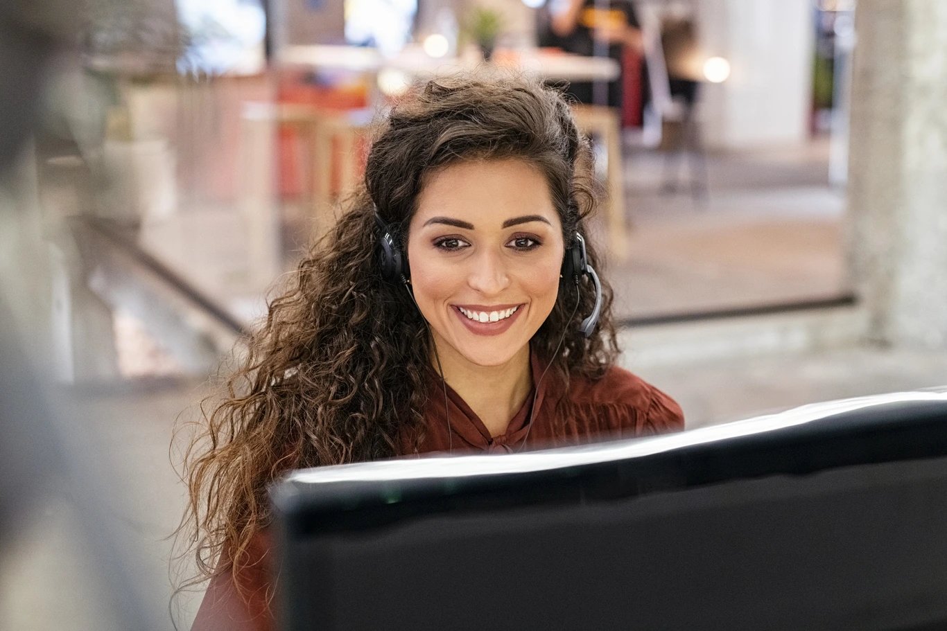 woman-smiling-with-headset-at-desktop-computer