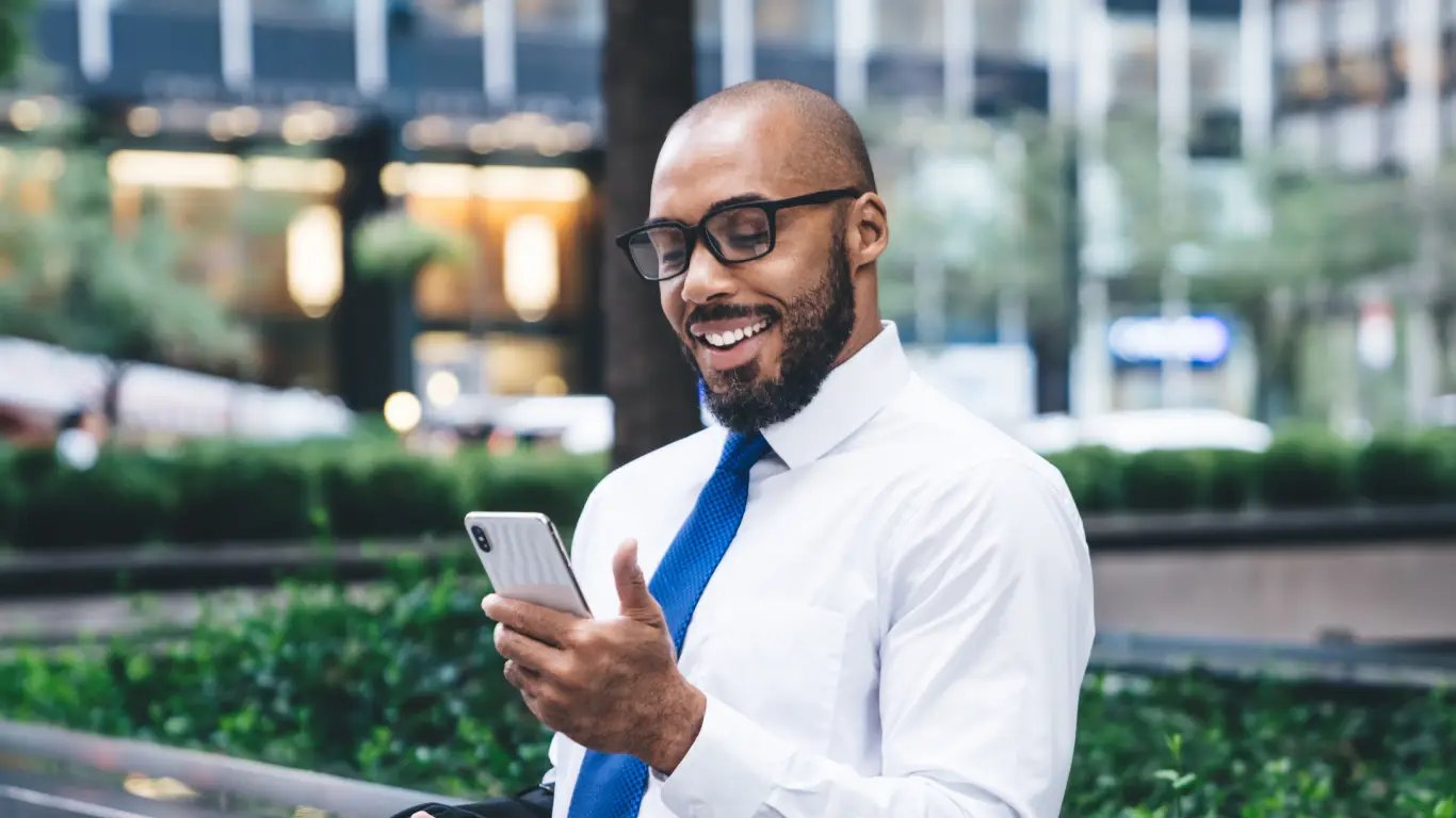 Man in tie outside looking at smartphone