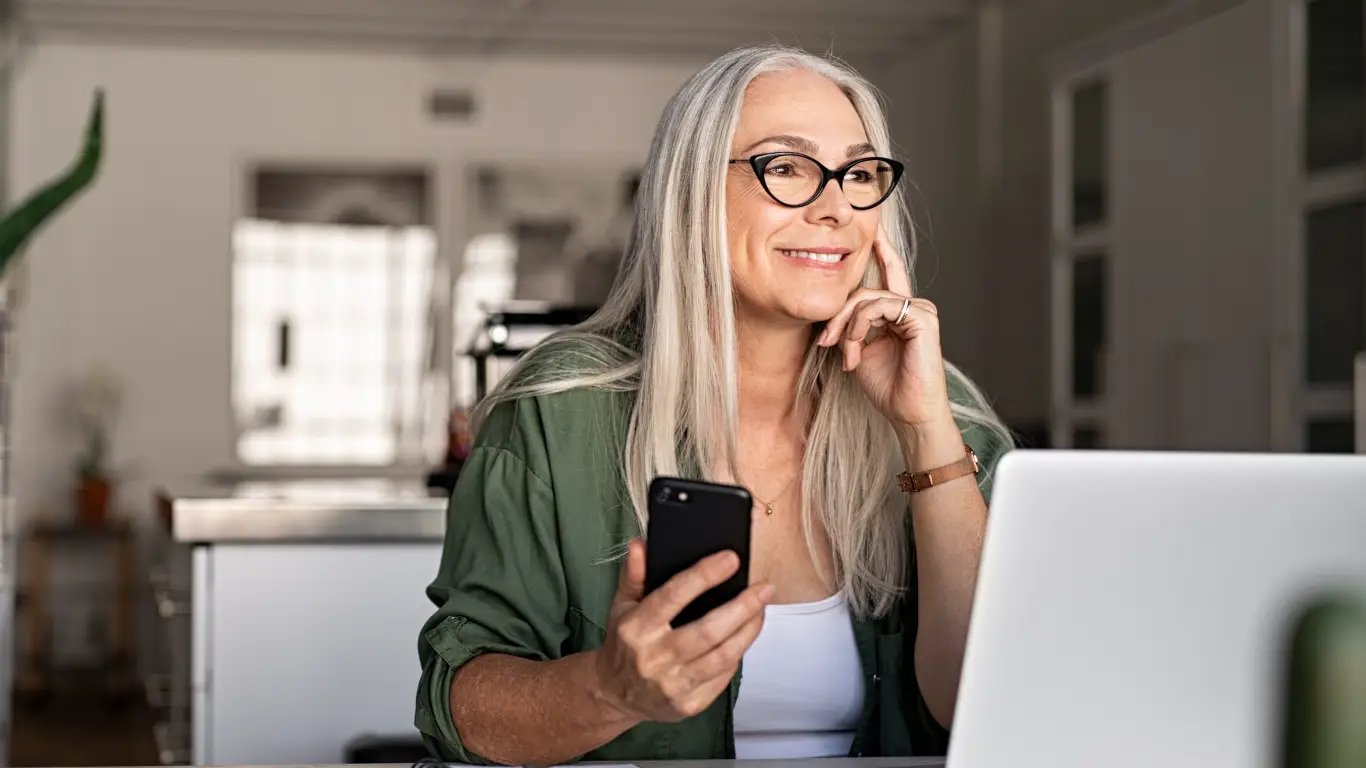 woman on laptop looking at smart phone